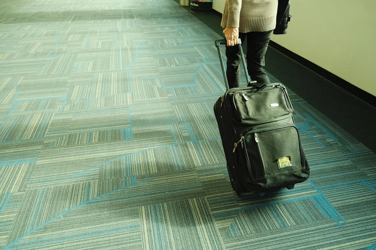 Traveller with a suitcase walking through an airport corridor