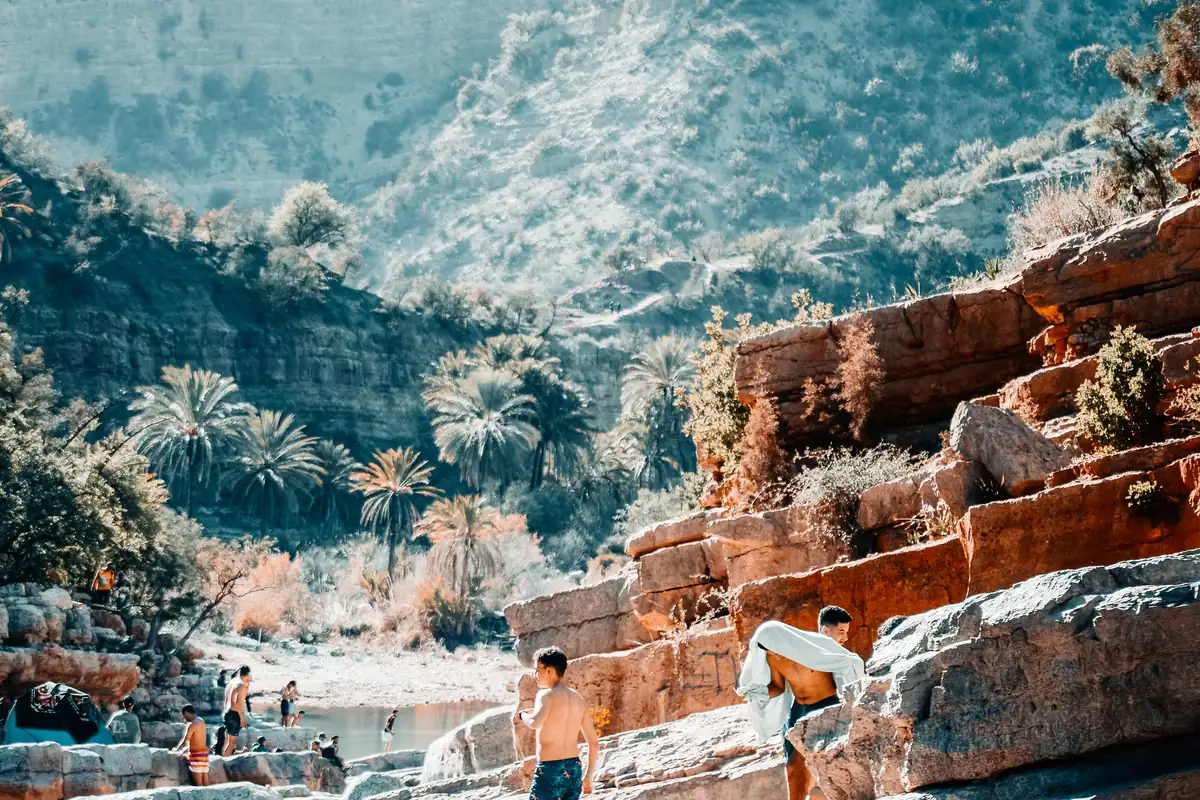 Rock pools and ochre cliffs of Paradise Valley, with palm trees and the Imouzzer hills