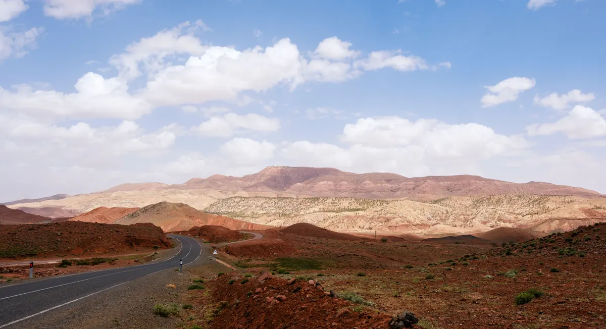 Winding road through red hills and the mountains of Morocco's Atlas